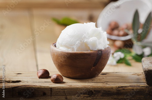 Foto Shea butter in wooden bowl with nuts on old rustic table