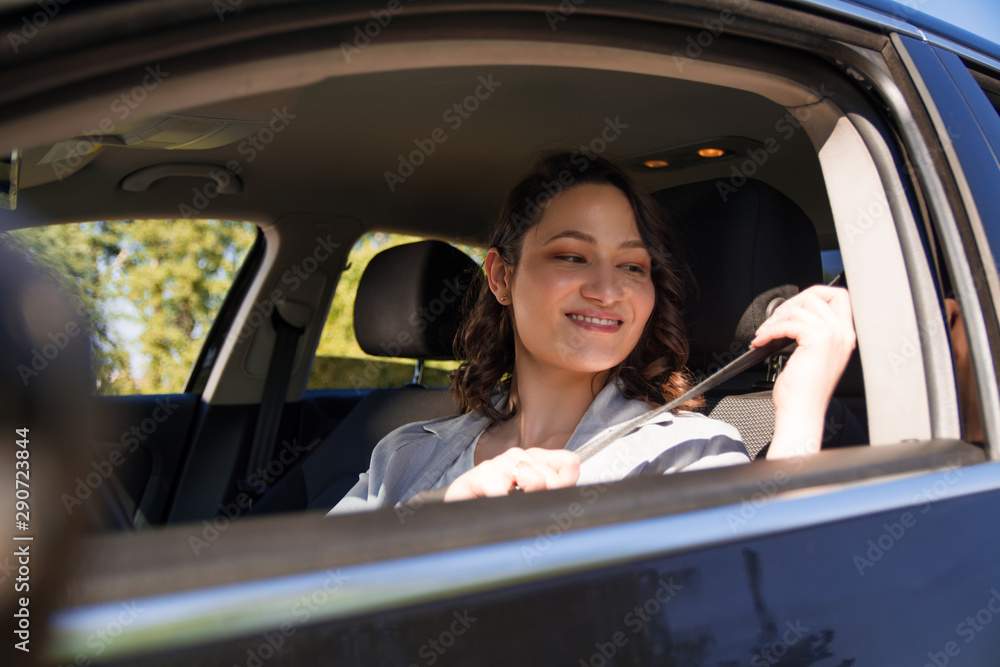 Beautiful businesswoman fastening seat belt in a car