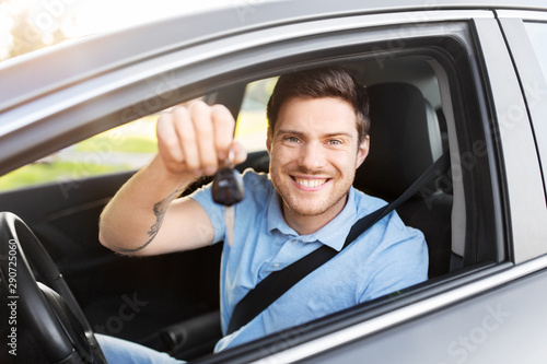 transport, vehicle and ownership concept - happy smiling man or driver with key sitting in car