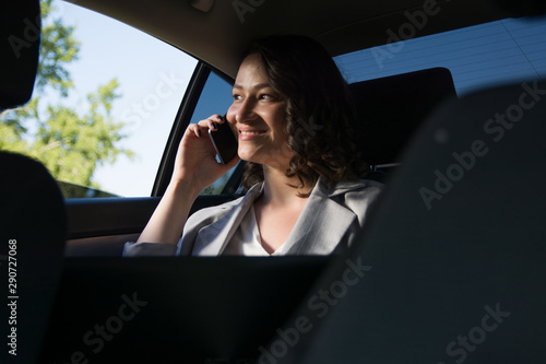 Smiling businesswoman using smart phone in the car