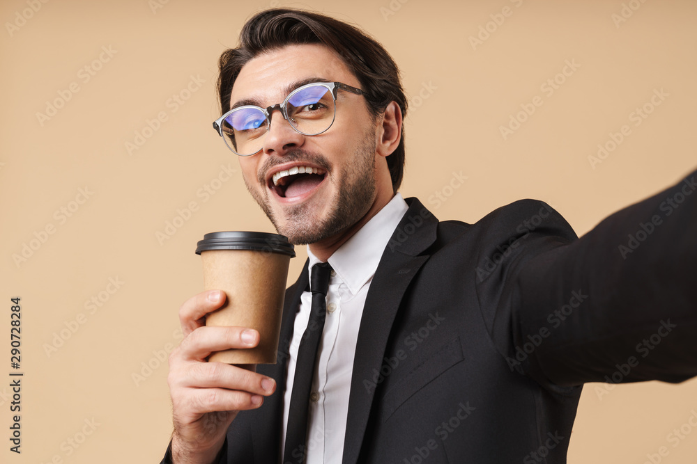 Image of happy businessman holding coffee cup while taking selfie photo Image of happy businessman holding coffee cup while taking selfie photo