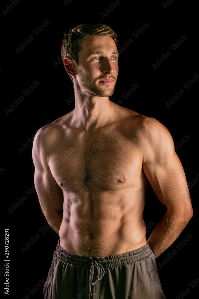 Muscular model young man on isolated black background. Sport workout bodybuilding concept. Strong bodybuilder fitness guy posing and demonstrating abdominal muscles abs and core. Muscular model young man on isolated black background. Sport workout bodybuilding concept. Strong bodybuilder fitness guy posing and demonstrating abdominal muscles abs and core.