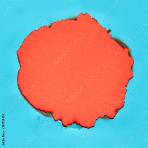 Vibrant color paper background with burnt hole in the middle