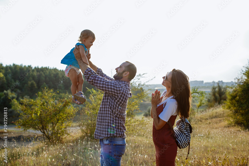 Fototapeta premium Happy family playing with her child at sunset.