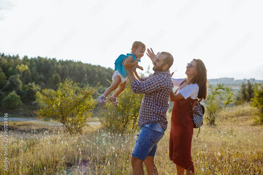 Fototapeta premium Happy family playing with her child at sunset.