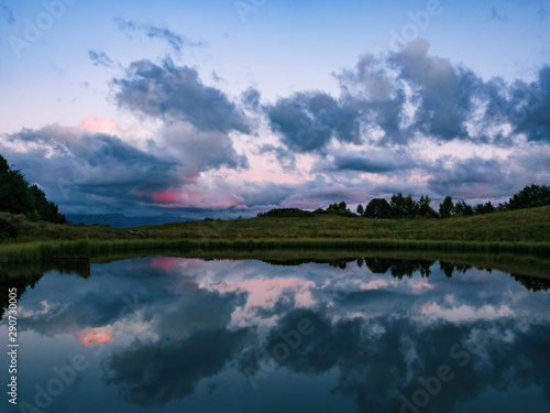Mirror reflection of clouds on lake or river water surface. Natural background at evening