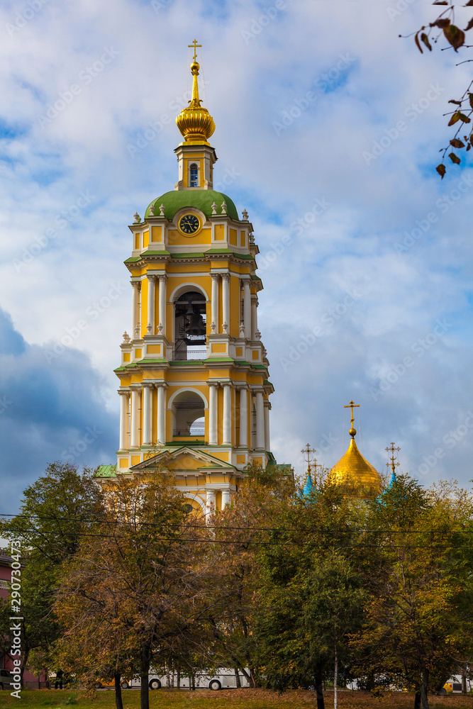The bell tower of the Novospassky Monastery with a clock against a picturesque cloudy sky (vertical image)