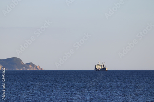 Foto Big fishing vessel at anchor near the rocky cape