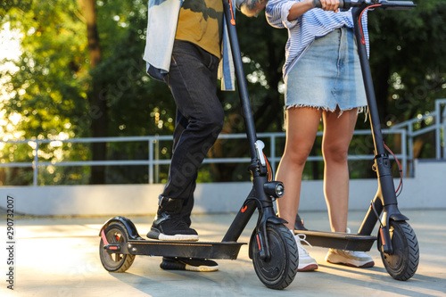 Cropped image of young caucasian couple smiling while riding e-scooters