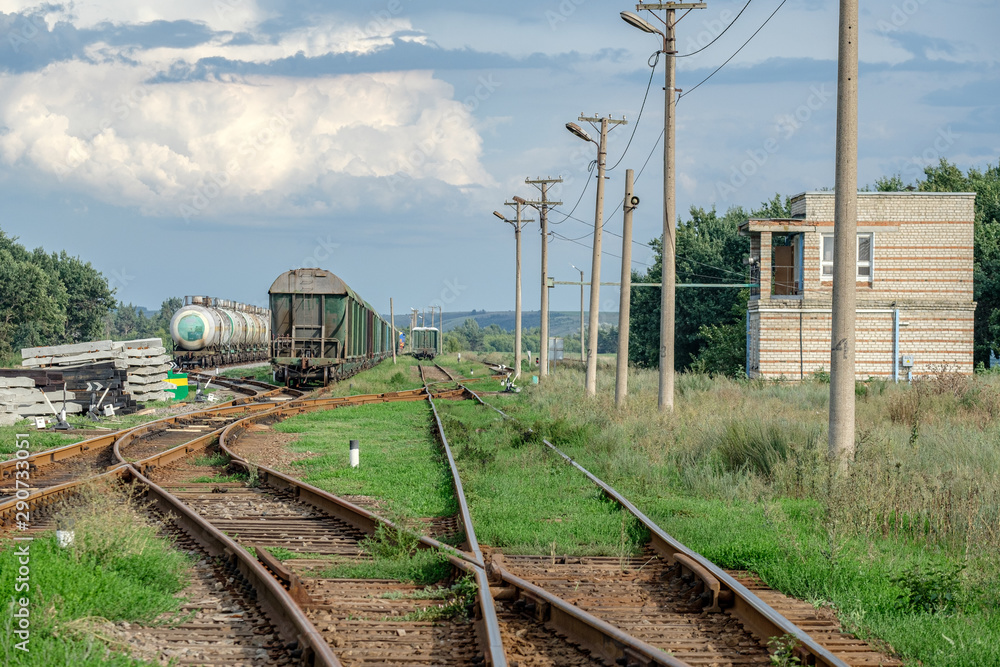 Train standing on siding on a sunny day in summer. Railway freight wagons and tanks of a different type and color. Train standing on siding on a sunny day in summer. Railway freight wagons and tanks of a different type and color.