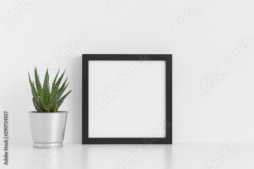 Black square frame mockup with a cactus in a pot on a white table. © Snoflinga