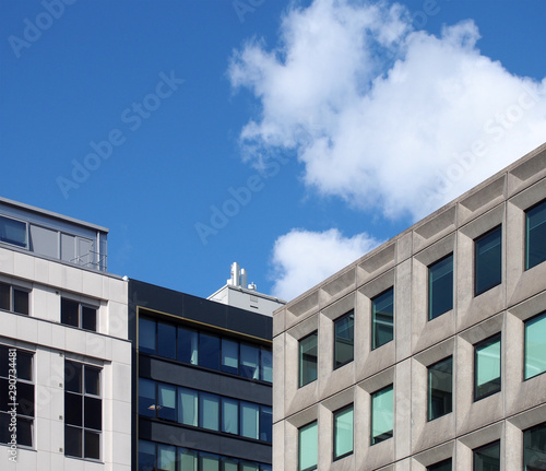 perspective corner view of a group of modern office buildings against a blue sky with clouds