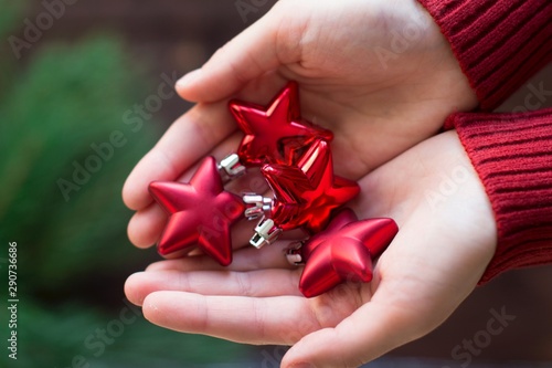 young woman in red christmas sweater holding red star christmas ornaments