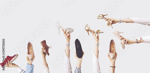Hands holding different shoes on isolated background