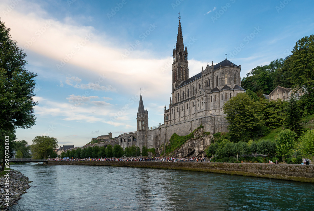 Side view of the sanctuary of Our Lady of Lourdes (France), next to the River Ousse, during the sunset.