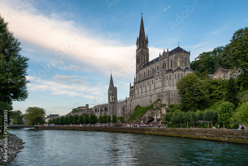 Side view of the sanctuary of Our Lady of Lourdes (France), next to the River Ousse, during the sunset. © cmassway