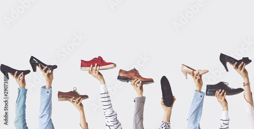 Hands holding different shoes on isolated background
