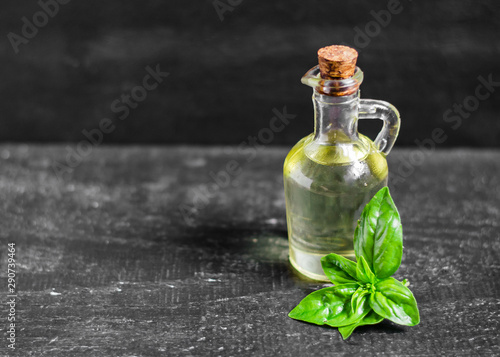 Basil oil and basil leaves on the dark background