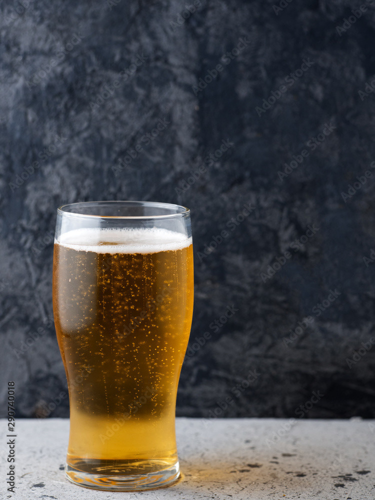 A glass of light beer on a dark background