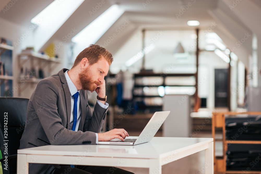 Side view of a serious businessman in formalwear looking at laptop. Side view of a serious businessman in formalwear looking at laptop.