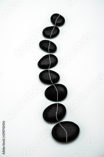Formation of black stones imitating the vertebral column, isolated in white background, conceptual image photo