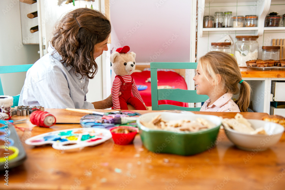 Fototapeta premium Mother and daughter playing with teddy bear in the kitchen