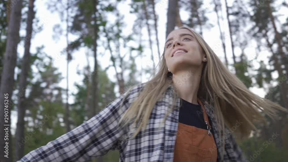 Portrait of happy beautiful girl in plaid shirt and hipster outfit smiling and spinning around herself on the background of beautiful forest. Slow motion Portrait of happy beautiful girl in plaid shirt and hipster outfit smiling and spinning around herself on the background of beautiful forest. Slow motion