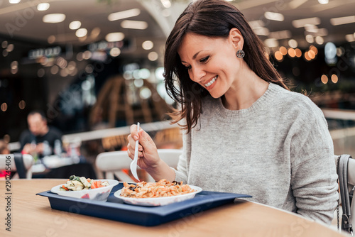 Portrait of a smiling woman eating lunch at food court.