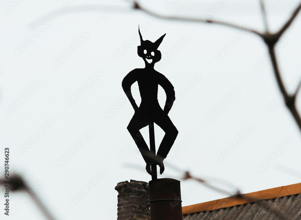 A dash figure made of metal and mounted on a chimney of a building