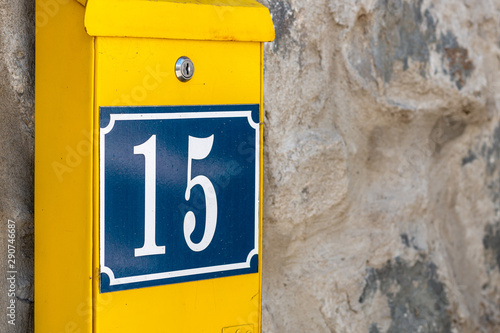 Yellow postbox on stone wall. Mailbox with number 15.