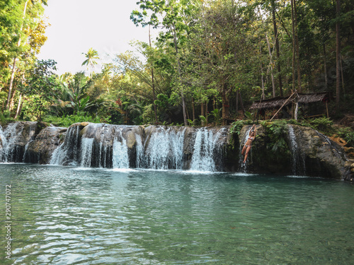 woman swinging with the rope at the pool of waterfalls  Cambugahay Falls on Siquijor Island in Philippines