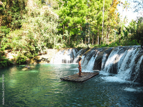 woman alone at the tropical wild nature adventure on the bamboo raft in Cambugahay Waterfalls in Siquijor Island, Philippines  photo