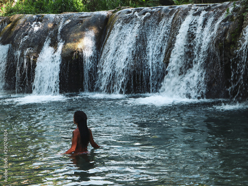 woman swimming alone at the tropical wild nature of waterfalls, cambugahay falls in Siquijor Island in Philippines photo