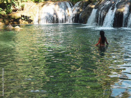 woman swimming alone at the tropical wild nature of waterfalls, cambugahay falls in Siquijor Island in Philippines