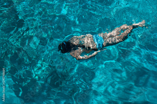 Top view photo. A young girl dives and snorkels in the clear turquoise Aegean Sea. Summer sea voyage and relaxation in a beautiful bay.