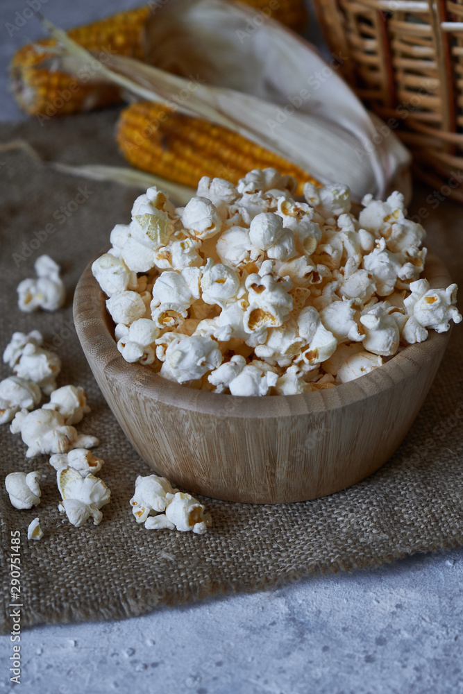 Traditional popcorn in a wooden bowl and corncobs on the table. Traditional popcorn in a wooden bowl and corncobs on the table.
