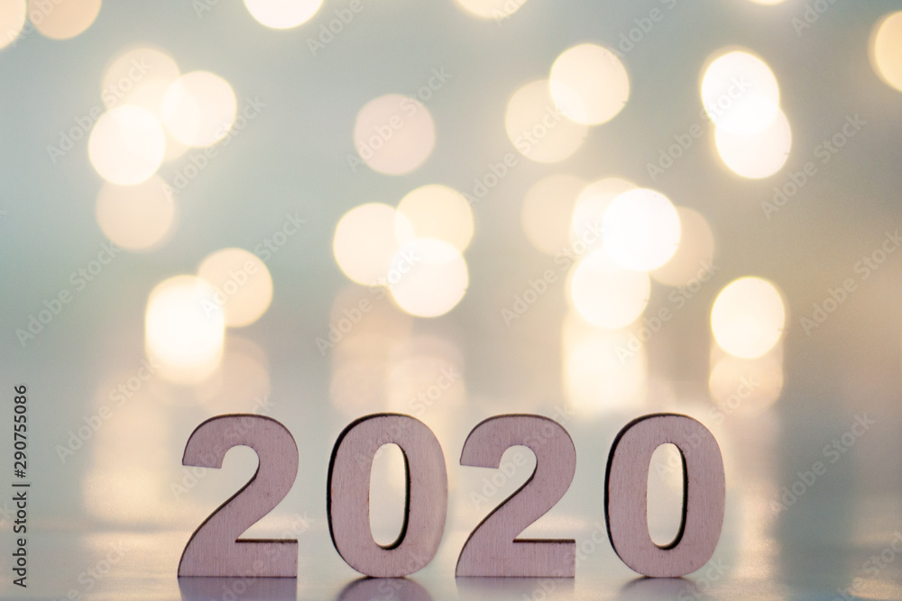 The inscription 2020, New Year and Christmas, from behind blurred dots of light on a blue background. Christmas and holiday.