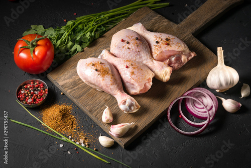 Raw chicken on a wooden board on a black background