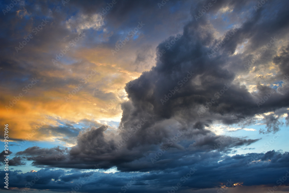 Storm clouds at sunset in orange and blue colors - obrazy, fototapety, plakaty 