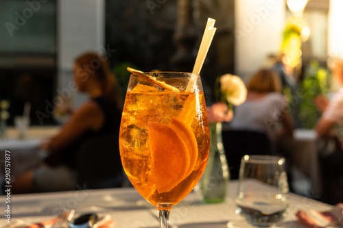 Glass of Aperol Spritz cocktail on the table in street restaurant, famous refreshing drink in sunny day photo
