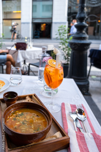Glass of Aperol Spritz cocktail  water and famous Hungarian soup gulyas on the table in street restaurant  in sunny day