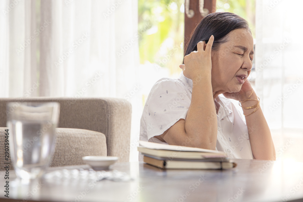 old age, health problem, vision and people concept - close up of Asian senior woman  sitting on sofa and having headache at home.She may had Headache Symptoms.She looks pain  and sick