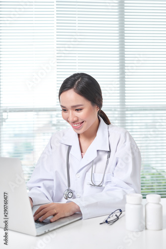 Female doctor working at office desk and smiling at camera
