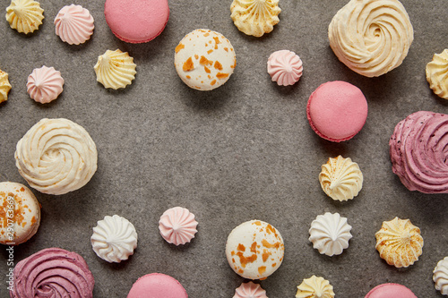Top view of pink and white macaroons with meringues on gray background