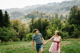 In waiting baby. happy family. pregnant woman with beloved husband walking on the grass. round belly.  Parenthood. The sincere tender moments, smiles. Husband holds the hand wife. mountains, forests