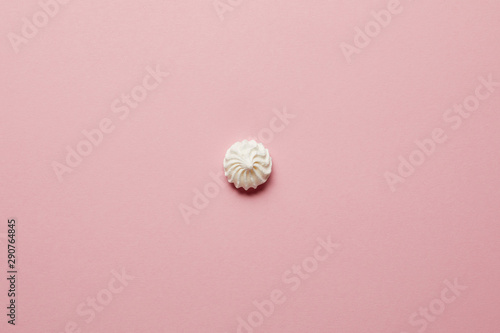 Top view of small white meringue in center on pink background