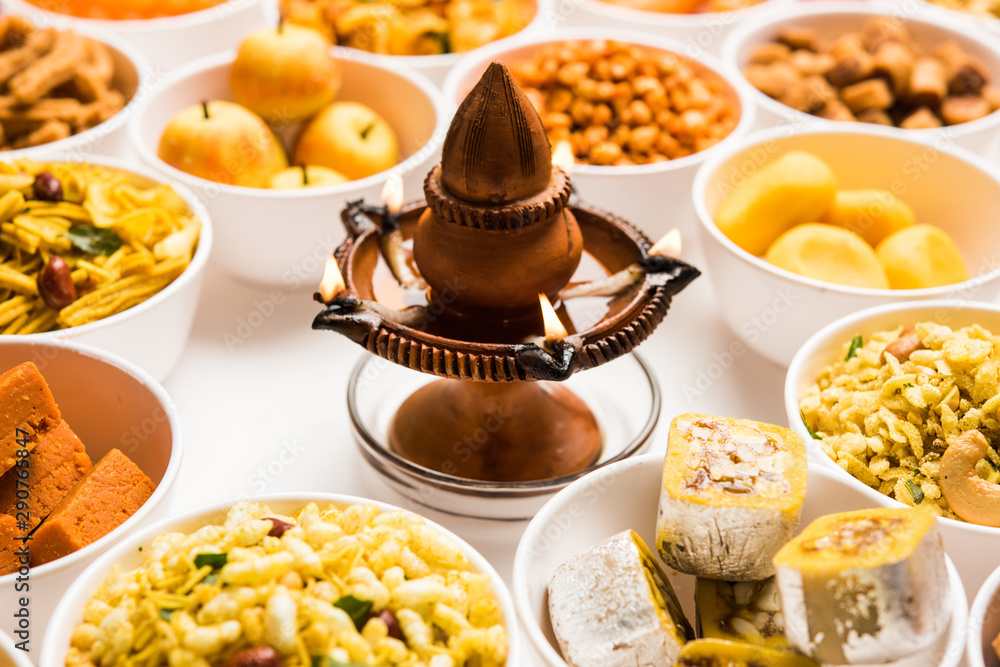 Rangoli of sweets and Farsan/snacks in bowls for Diwali with diya over white background Rangoli of sweets and Farsan/snacks in bowls for Diwali with diya over white background