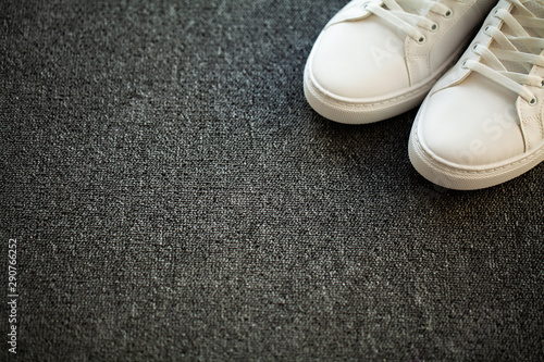 Pair of new stylish white sneakers on floor at home