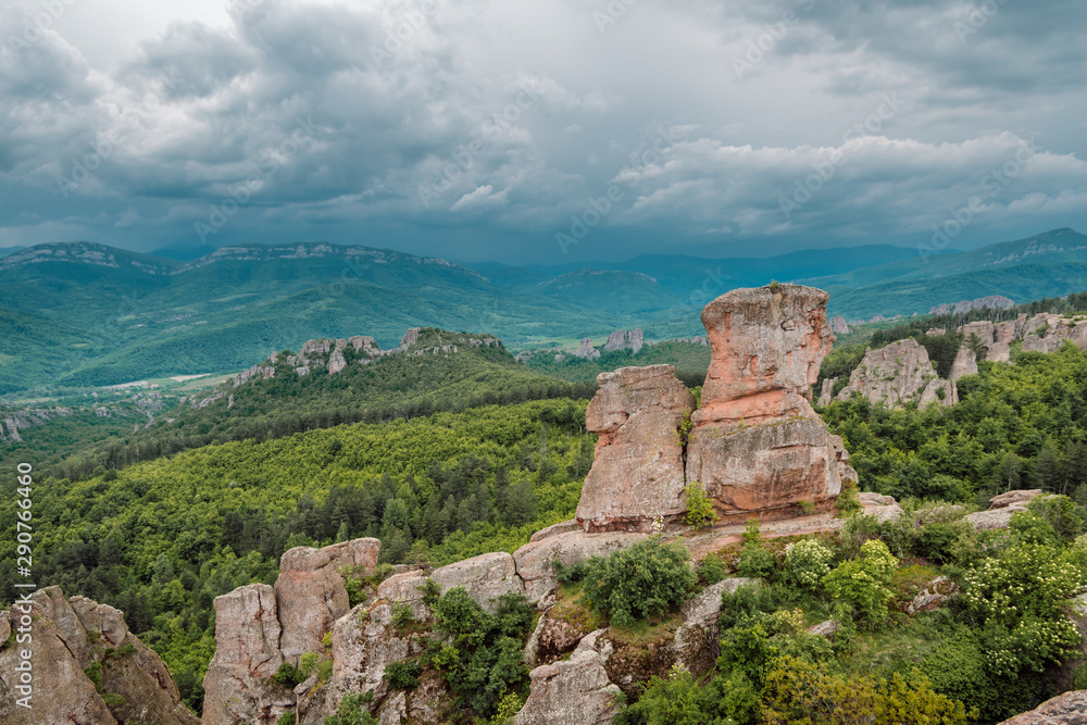 Stormy sky over beautiful rocky formations. With their red color they contrast beautifully with the green broadleaf forests below and the lush meadows, Belogradchik Rocks, Bulgaria. 