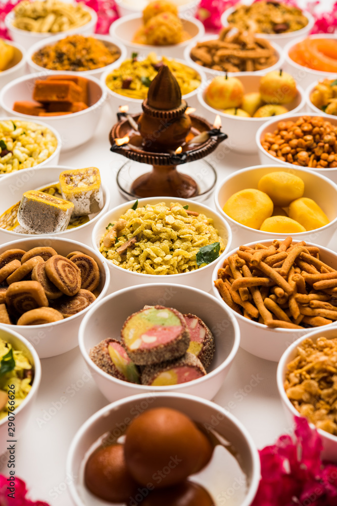 Rangoli of sweets and Farsan/snacks in bowls for Diwali with diya over white background Rangoli of sweets and Farsan/snacks in bowls for Diwali with diya over white background